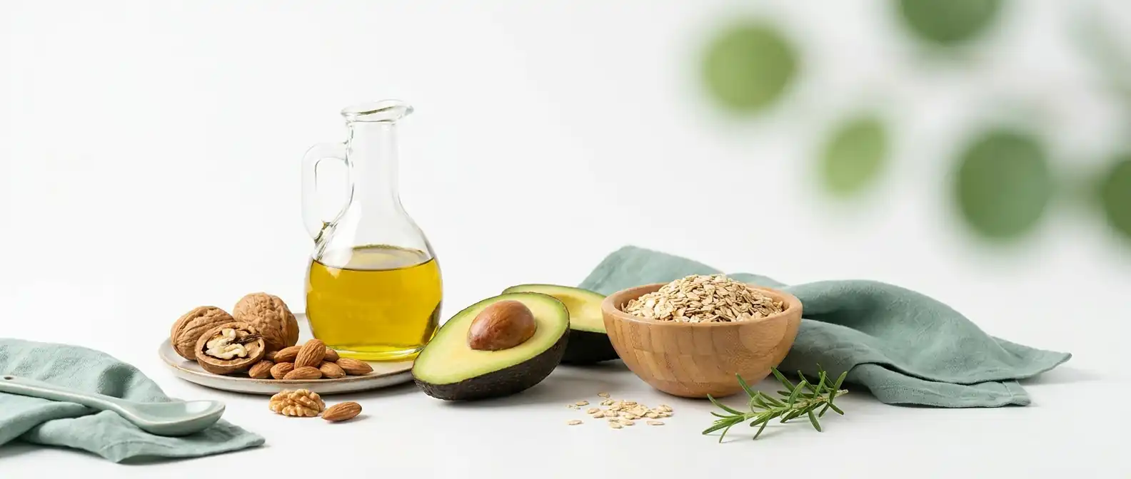 Herzgesunde Lebensmittel auf hellem Untergrund — Olivenöl, Nüsse, Avocado und Haferflocken als Sinnbild für gesunde Blutfette