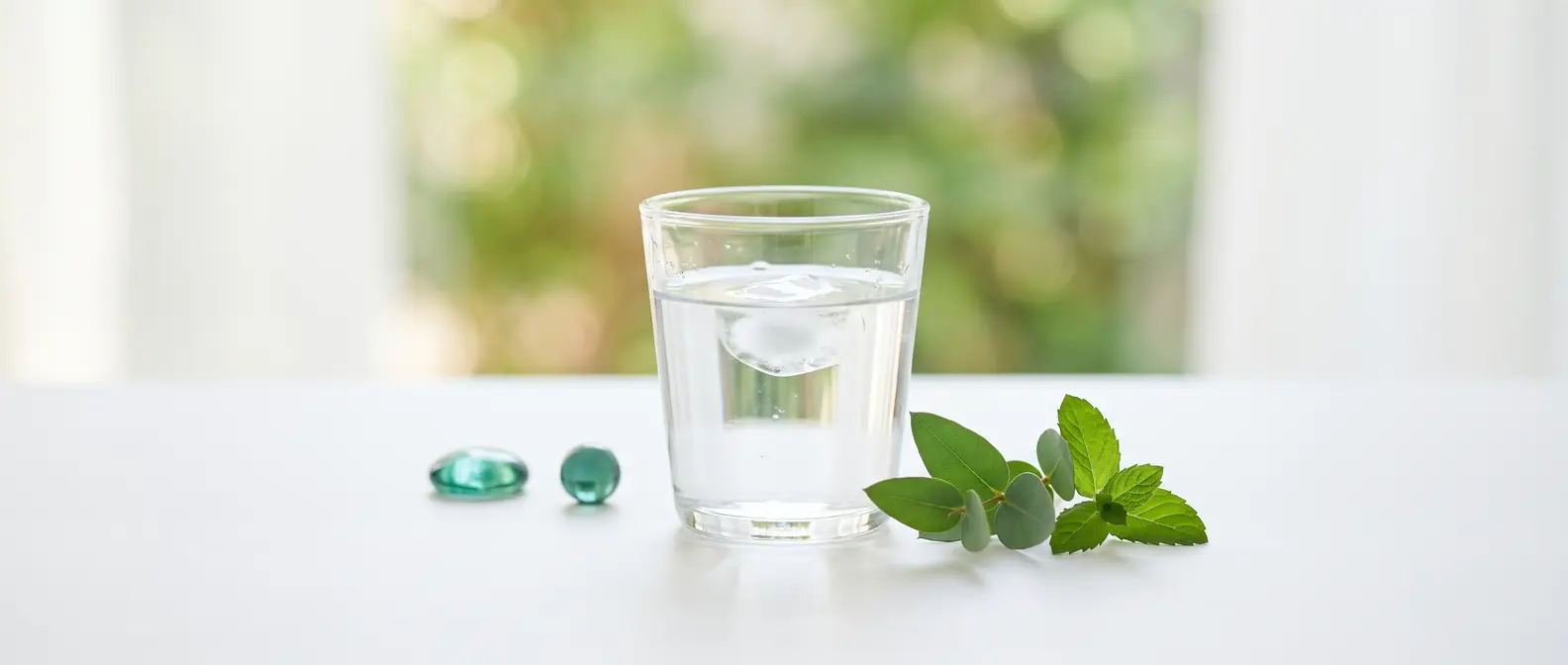Ein Glas Wasser mit frischen grünen Blättern auf hellem Untergrund mit Teal-Akzenten — Lipase und Bauchspeicheldrüse unter GLP-1