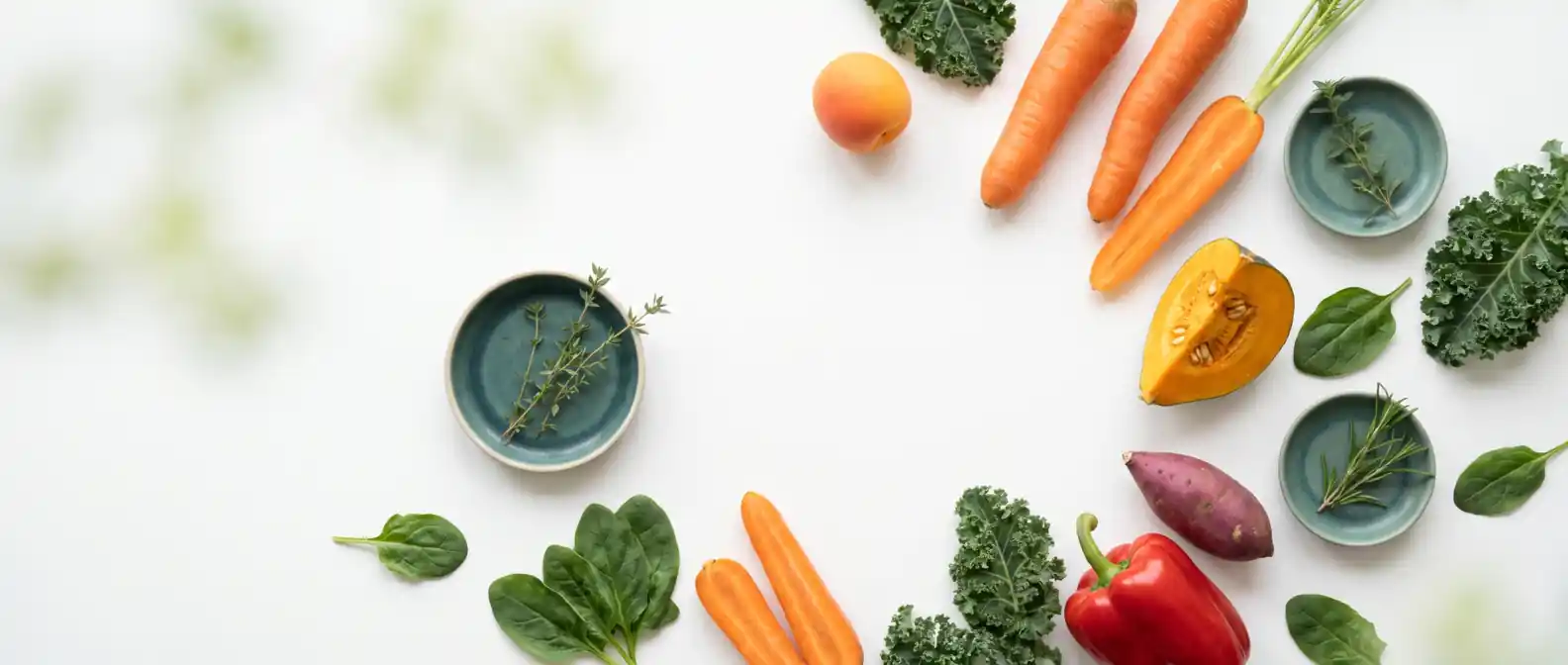 Beta-carotinreiche Lebensmittel wie Karotten, Kürbis, Süßkartoffel, rote Paprika, Aprikose und Grünkohl hell und clean auf weißem Untergrund mit tealfarbenem Akzent und grünem Bokeh — Vitamin A unter GLP-1